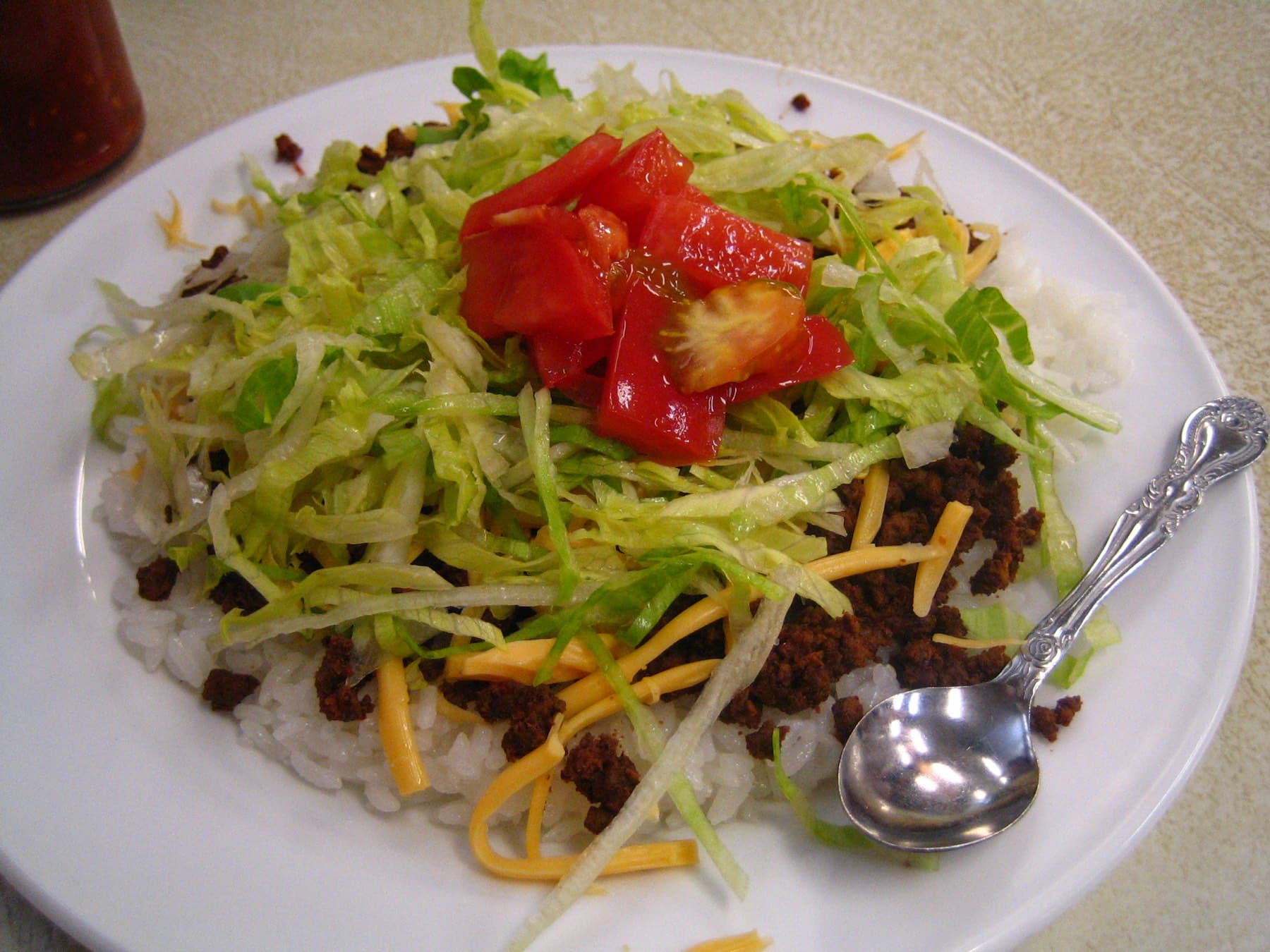 Seasoned ground beef, grated cheddar, shredded lettuce and chopped tomato are heaped on white rice on a plate at Jack's Steak House in Naha